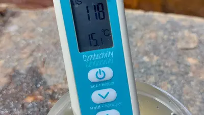 A handheld conductivity meter in a water sample.